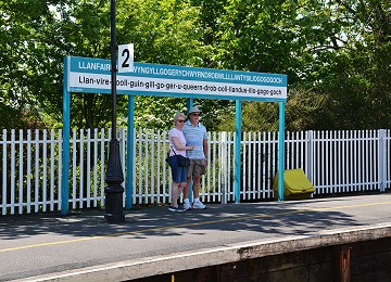 Tourists have their photograph taken by the long sign on Llanfairpwll railway station