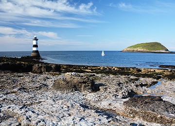 Trwyn du lighthouse with puffin island and yacht sailing