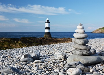 Pebble tower on Penmon Point beach with Trwyn Du lighthouse in distance